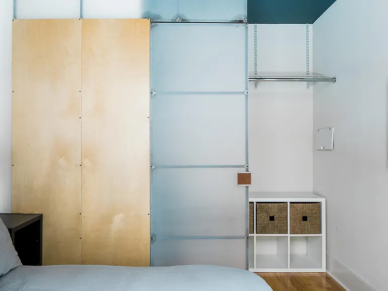 Bedroom includes designer furniture with under-bed storage, as well as custom designed feature closet door