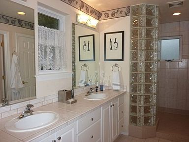 Master bathroom offers high quality double vanity with glass block walk in shower and tile counters.