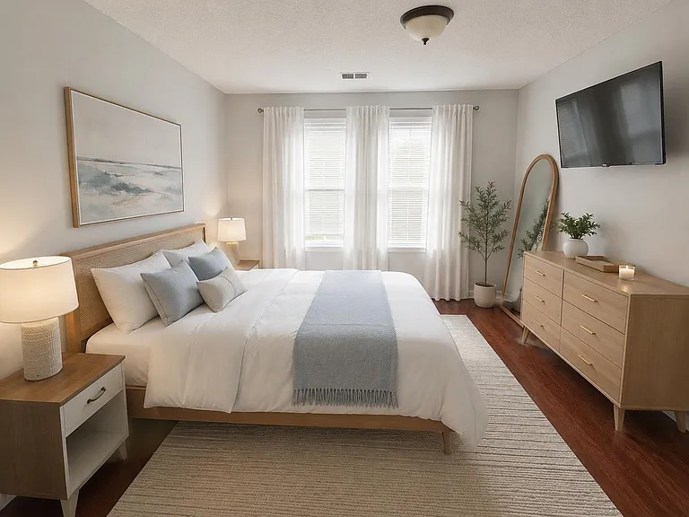 Well-appointed bedroom with a full bed, dual windows with curtains, a spacious dresser, and a wall-mounted TV.