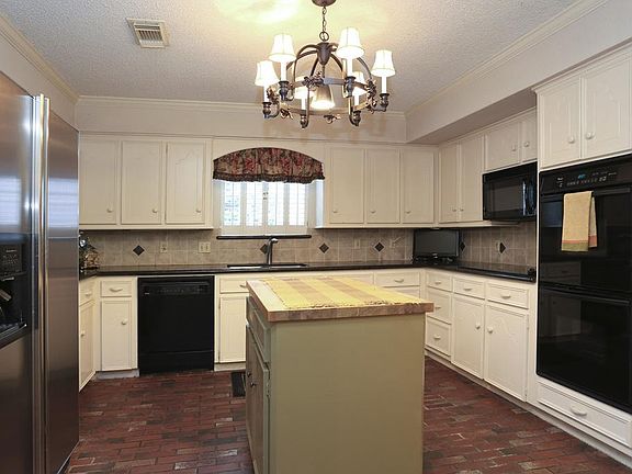 Light, bright and open style kitchen with job built solid wood cabinetry, granite counters, tile back splash, butcher block topped center island and antique brick style flooring.