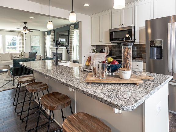 Island kitchen and adjacent living room in a DRB Homes York II model at the Townes at Tate Manor com