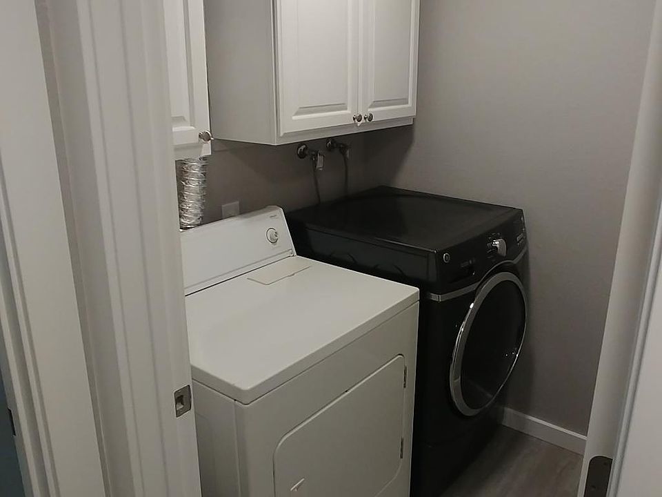 washer and dryer in the unit with white cabinet for storage