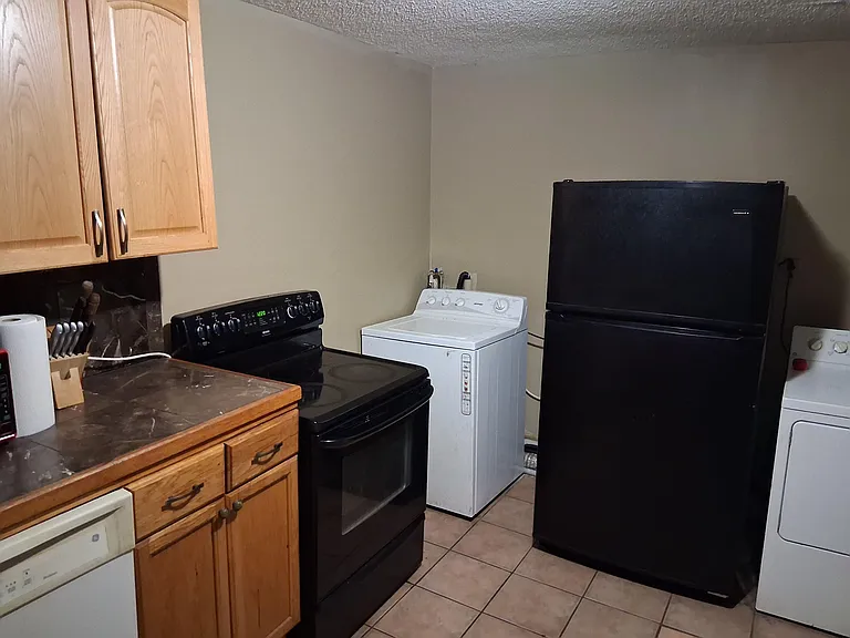Compact kitchen with ample wood cabinetry, full appliance set, and an in-unit laundry nook for added convenience.