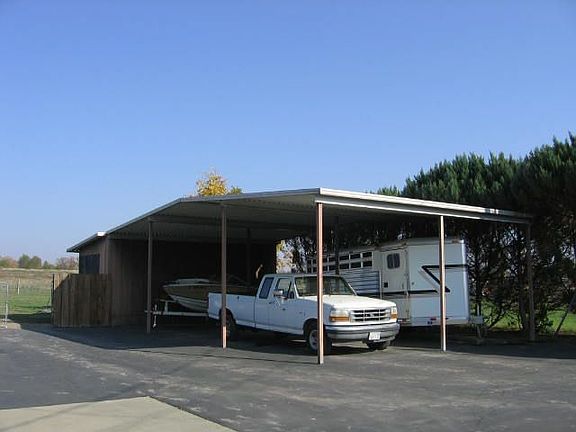 RV-height multi-vehicle carport and storage room behind.