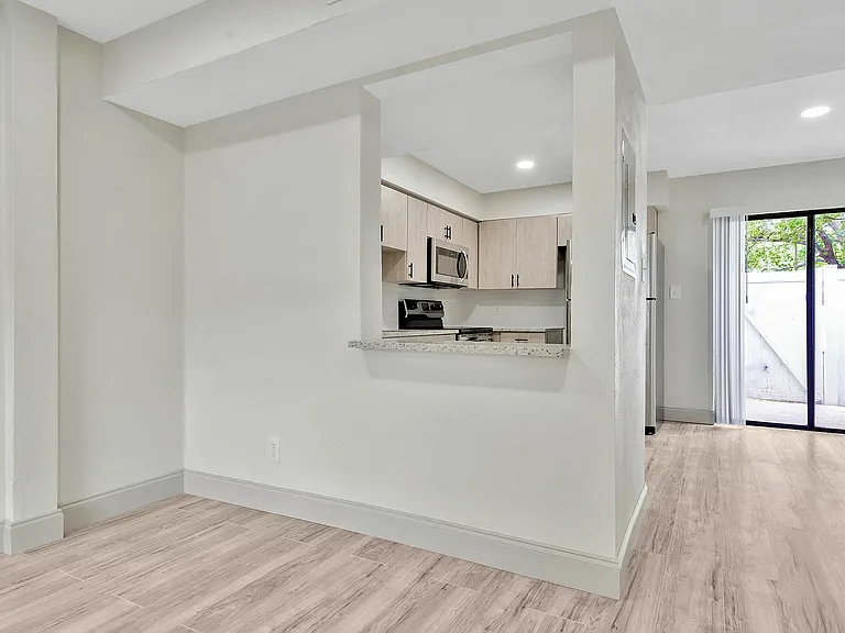 Modern kitchen with sleek cabinetry, granite countertops, and bright open layout leading to a private patio.