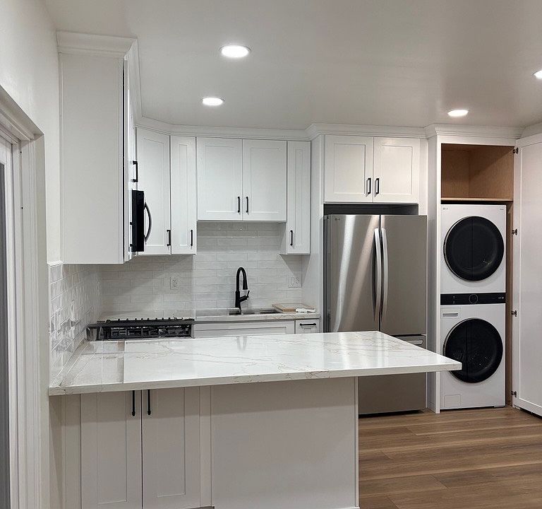 Kitchen view from living room- full gas range, microwave, sink, full refrigerator, washer/dryer, and AC in this space