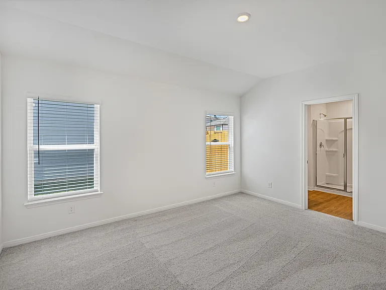 Master bedroom with two windows and lush carpet.