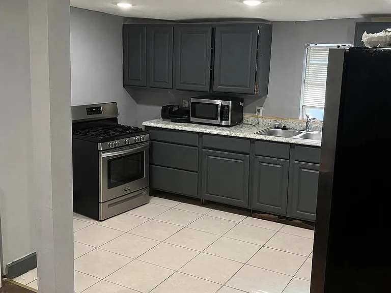 Efficient kitchen with ample cabinet storage, full-size gas range, double sink, and generous counter space for meal prep.