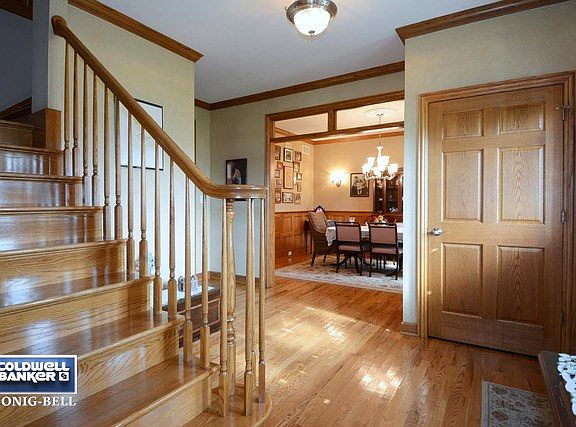 Spacious Foyer with Custom Turned Staircase, Hardwood Floors, Crown Molding, & 6 Panel Oak Doors