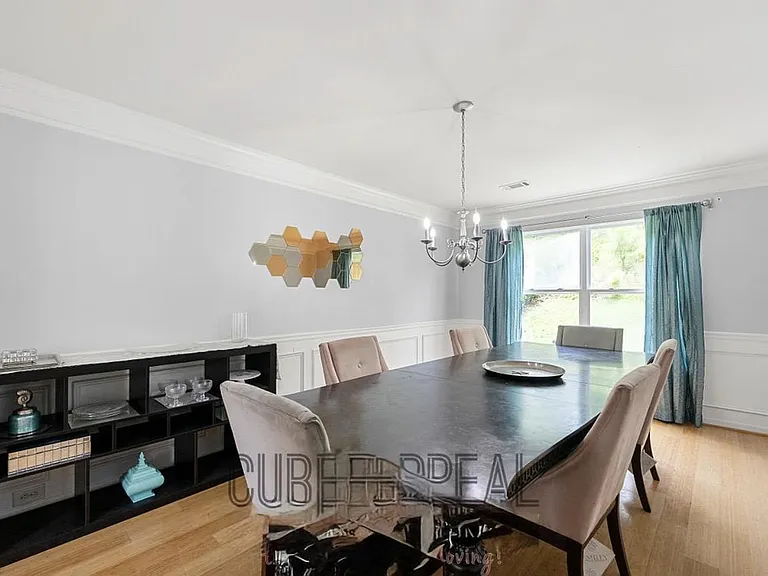 Formal dining room with wainscoting, chandelier lighting, and a large windowideal for shared meals and gatherings.