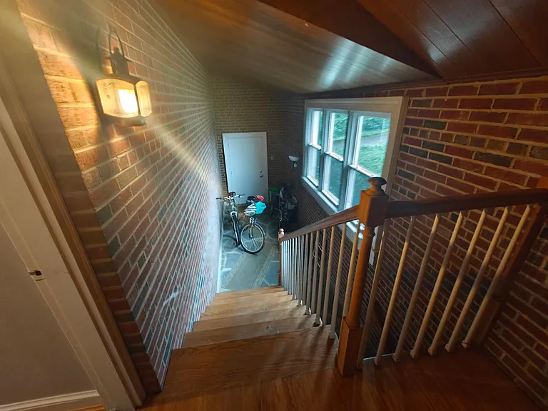 Mudroom with entrance from driveway by garages and inner stairway below to garage.