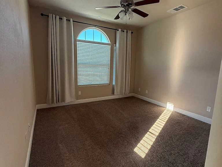 Bedroom with beautiful ceiling fan and black out curtains.