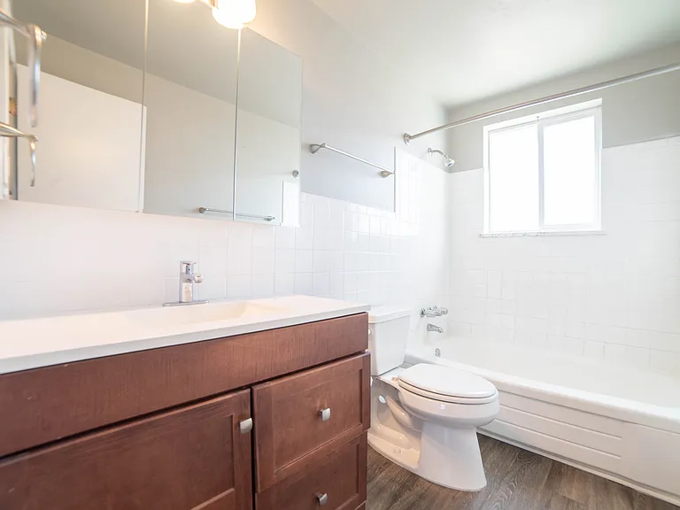 Bright and modern bathroom featuring a sleek wood vanity, pristine bathtub, and elegant tilework.