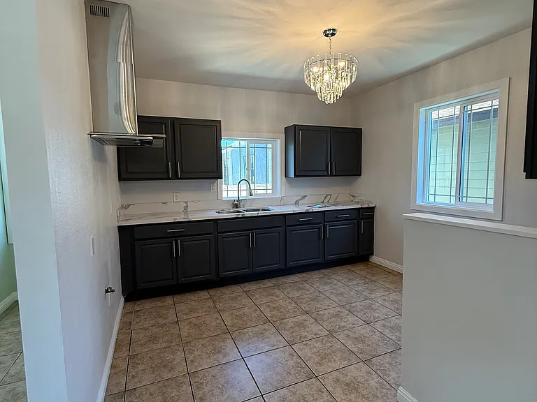 Kitchen area with new countertop, new sink, new kitchen range hood, new light fixture, new windows, fresh paint