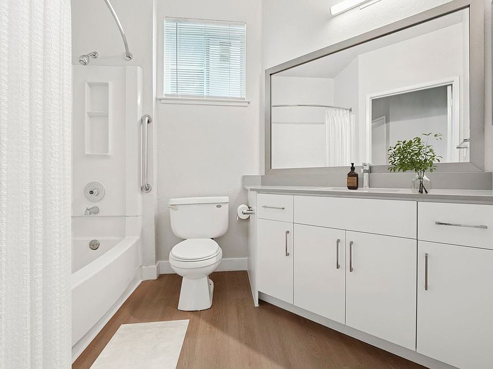 Renovated Package I bath with white cabinetry, grey quartz countertops, and hard surface flooring