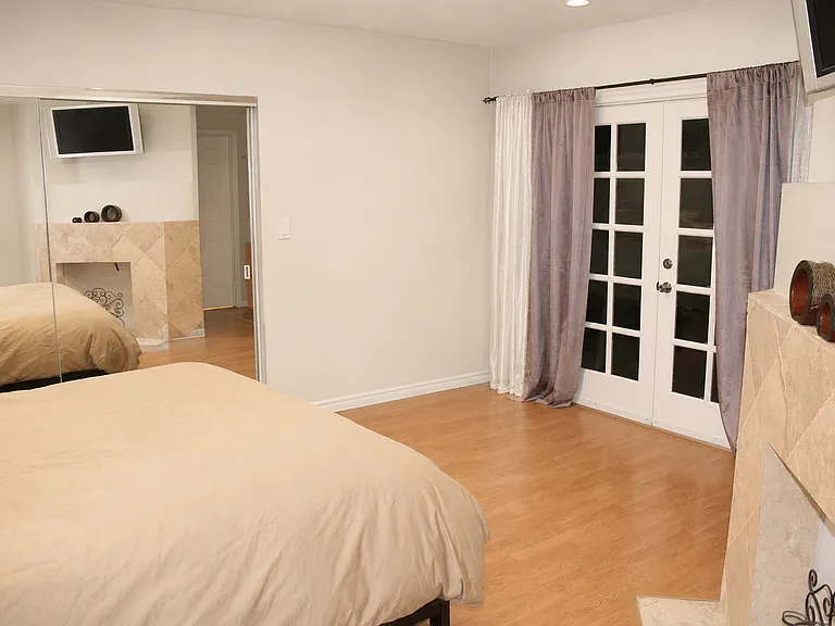 Master bedroom with large mirrored closet and french doors to backyard.