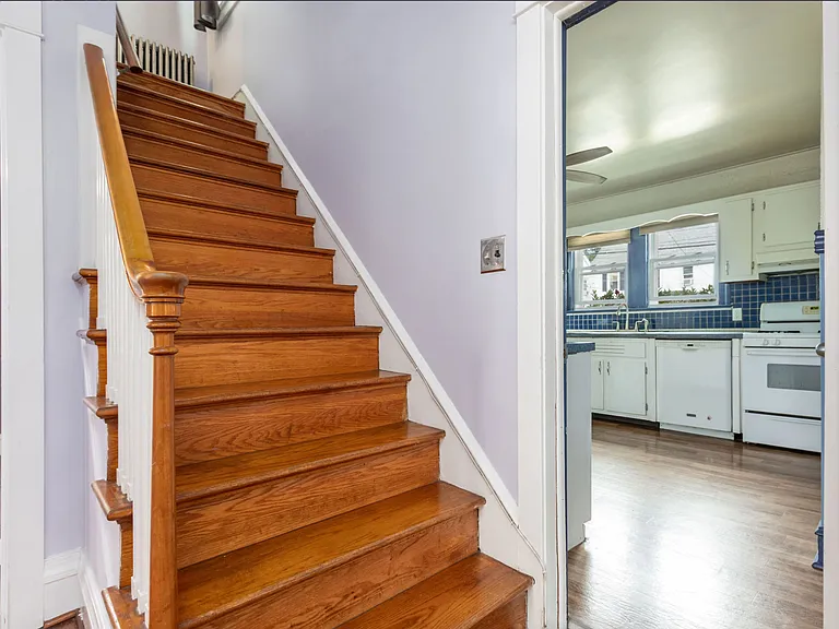 Stairs to 3rd bedroom on 2nd floor and half bathroom. View into kitchen.