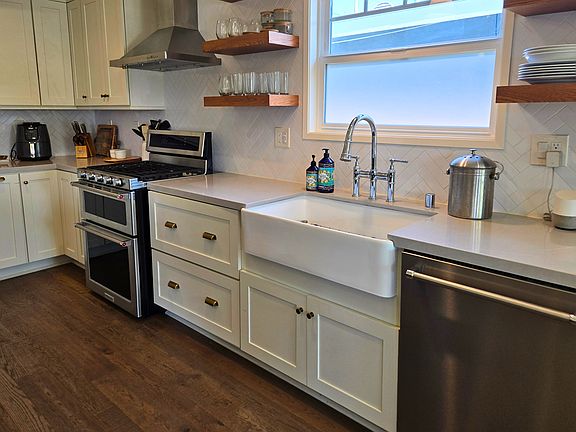 Chef's kitchen with farmhouse sink, KitchenAid dishwasher, and stainless steel gas range for modern South Bay living.