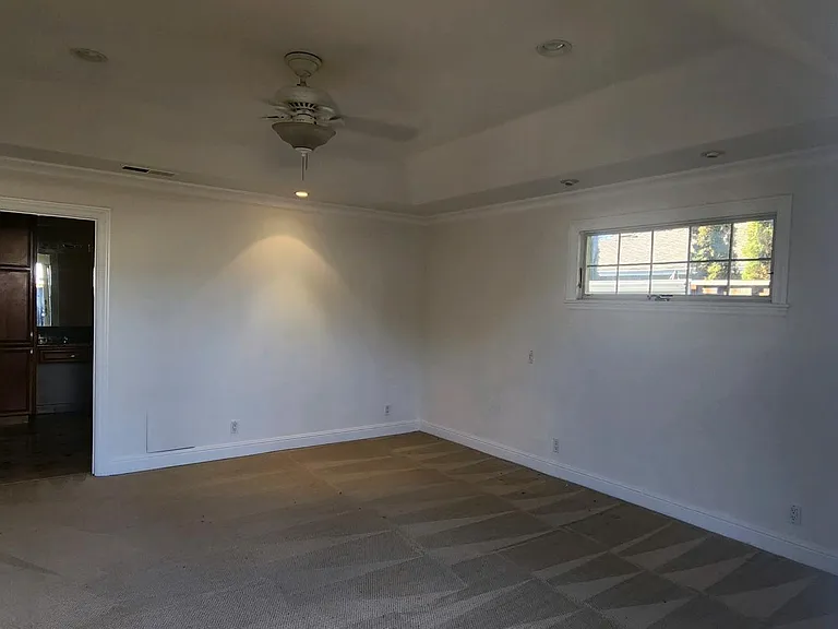 Primary bedroom view from sliding glass doors into large private bathroom.