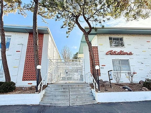 Charming mid-century modern apartment building with unique brick and colorful accents, surrounded by serene landscaping and mature trees.