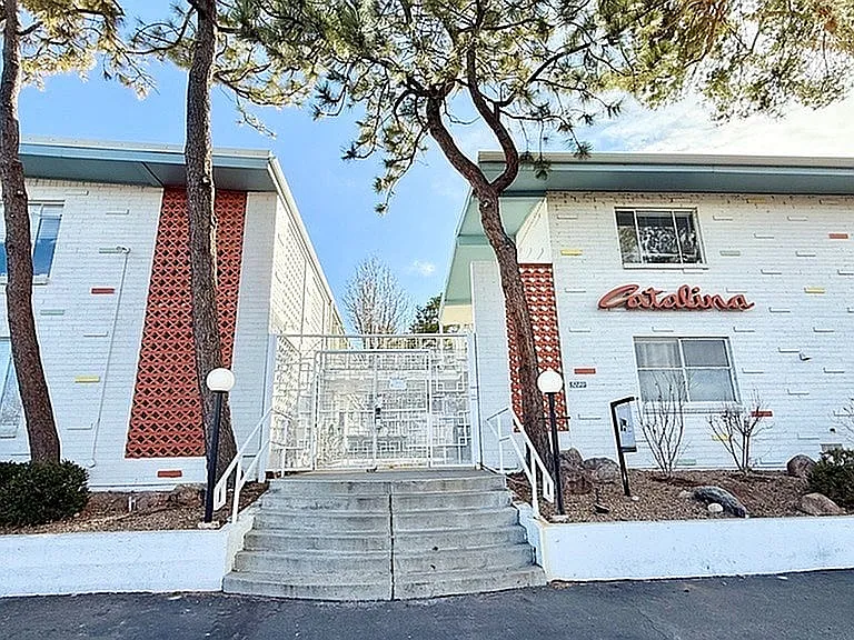 Charming mid-century modern apartment building with unique brick and colorful accents, surrounded by serene landscaping and mature trees.