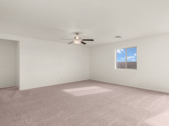 Spacious family room with large windows and a ceiling fan.