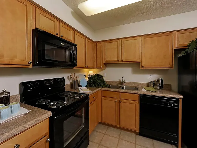 Classic Package II kitchen with oak cabinetry, beige laminate countertops, black appliances and tile flooring