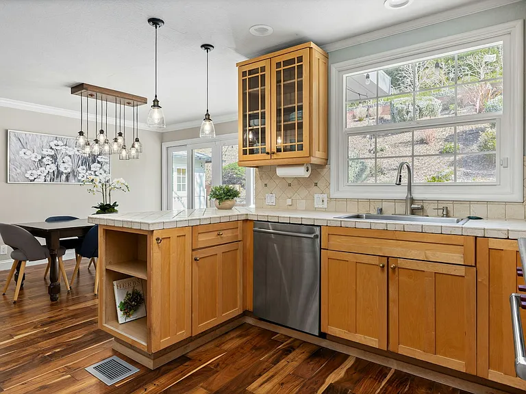 Light-filled and functional this charming kitchen features a spacious island, updated dishwasher, and a picture window with garden views, flowing seamlessly into the dining area for easy family meals or entertaining.