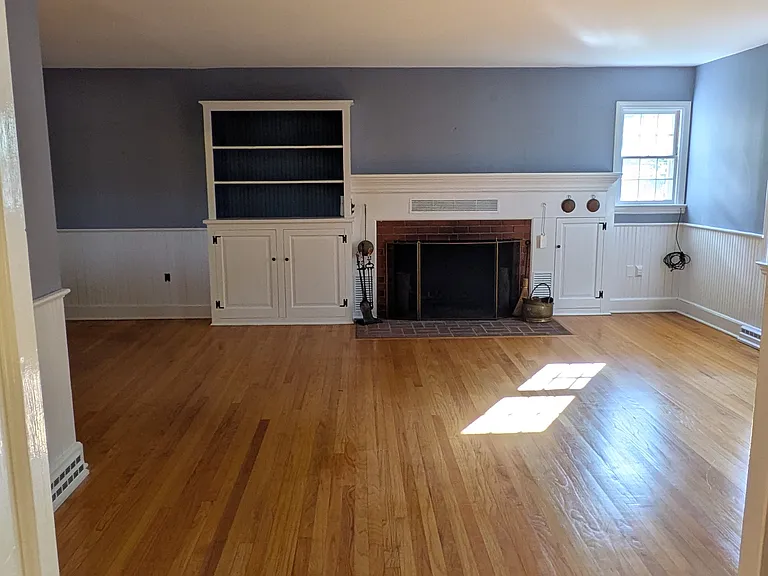 Large living room with wood burning fireplace and built in shelves