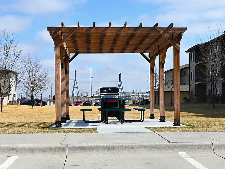 A wooden pergola with a table and grill at The Sterling.