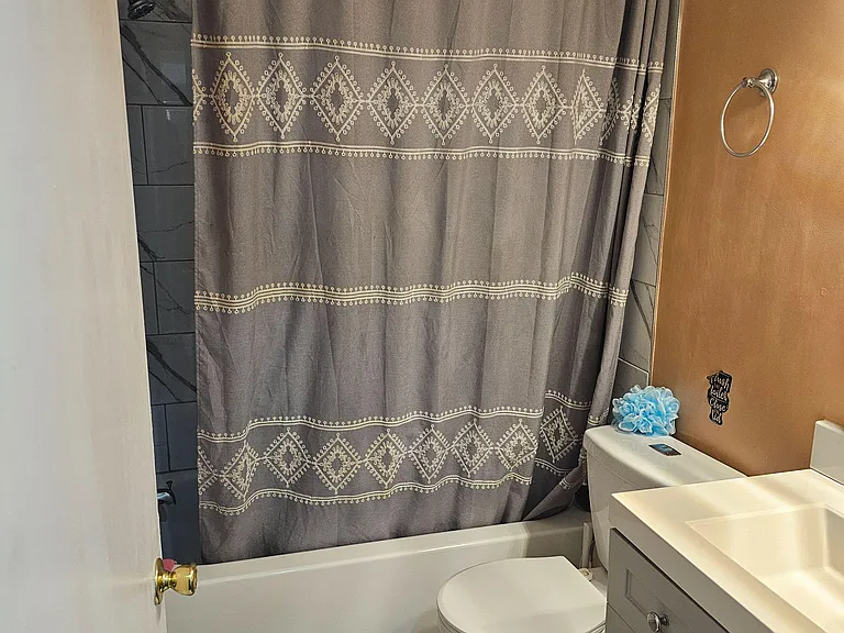 Full bath with a tub/shower combo, tiled surround, and a vanity with storage for everyday essentials.