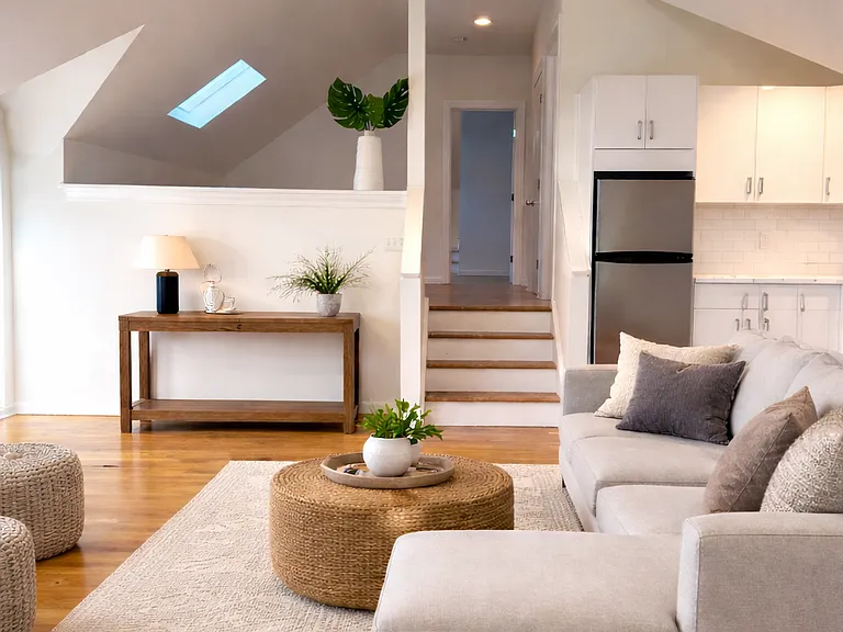 Living room different view virtually staged. A multi-level layout is visible, with a short staircase leading to private den and a bedroom.