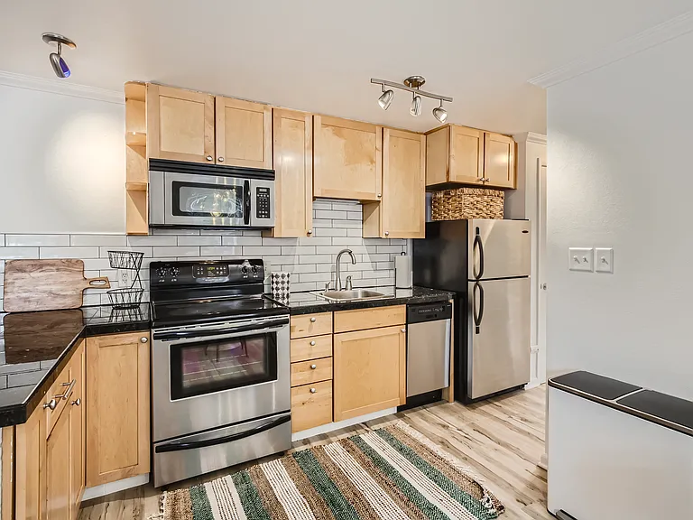 The kitchen features sleek granite tile countertops, modern subway tile backsplash, stainless steel appliances, & all the kitchen tools needed for your extended stay. There is also a full-sized pantry for extra storage.