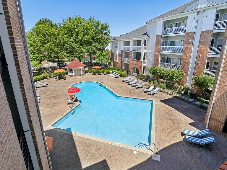 Serene swimming pool with lounge seating, patio tables, and umbrellas