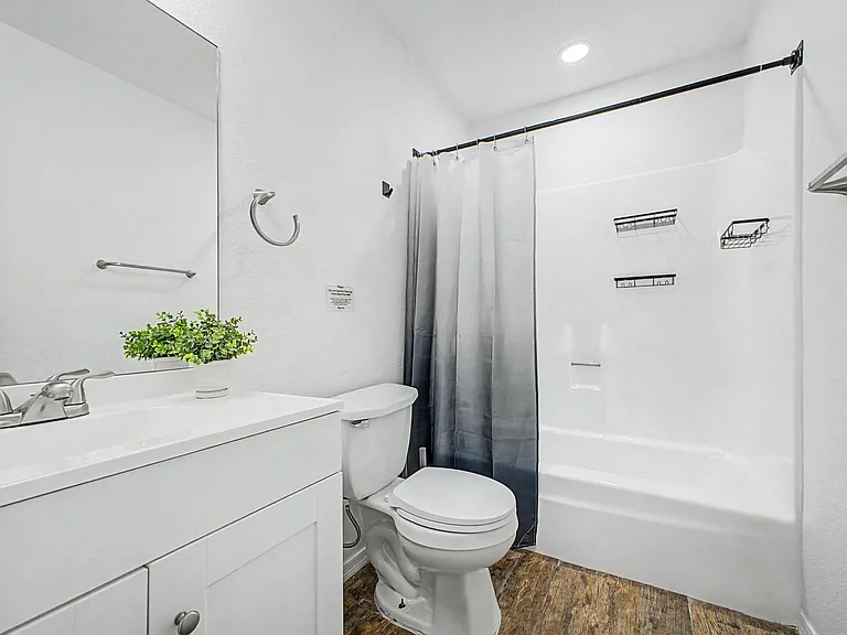 Full bathroom with a tub/shower combo, vanity with storage, and built-in shower shelving for everyday organization.