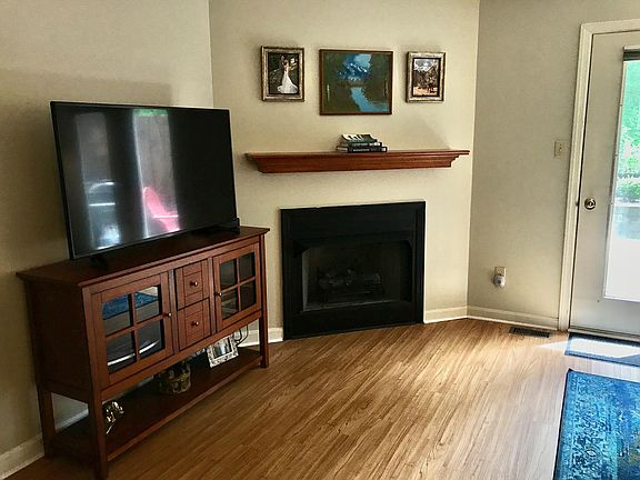 Living room showing corner fireplace, wood floors and patio door
