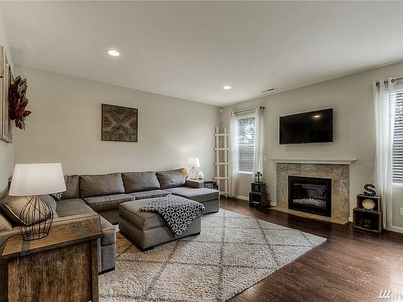 The light-filled living room features a cozy gas fireplace with tile surround & white mantle. 