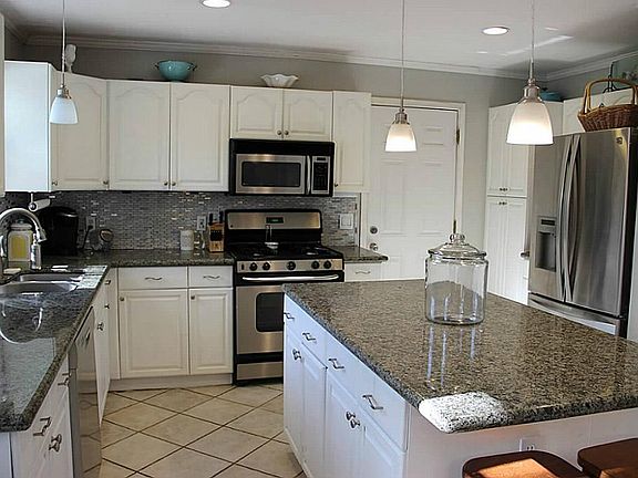 White Cabinets, Granite Countertops, Beautiful Backsplash, and Stainless Steel Microwave, Dishwasher