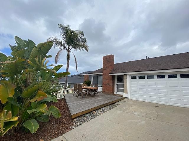 Front deck hidden from street by giant birds of paradise; note 2 car garage and generous flat driveway for play or parking
