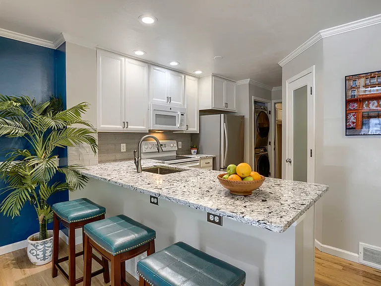 Renovated Kitchen, Pantry & In-Unit Laundry _ Updated kitchen featuring a statement quartz countertop, white cabinetry, a floor-to-ceiling pantry, new Bosch dishwasher, Whirlpool refrigerator, range, microwave and Samsung smart stackable washer and dryer.