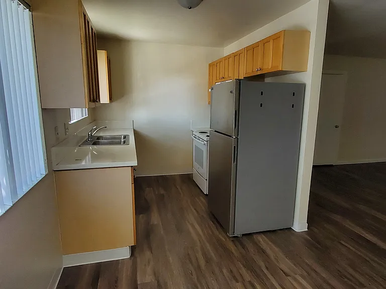 Kitchen and dining area with large window and hardwood flooring at Zenith Place Apartments in Chula Vista, California.