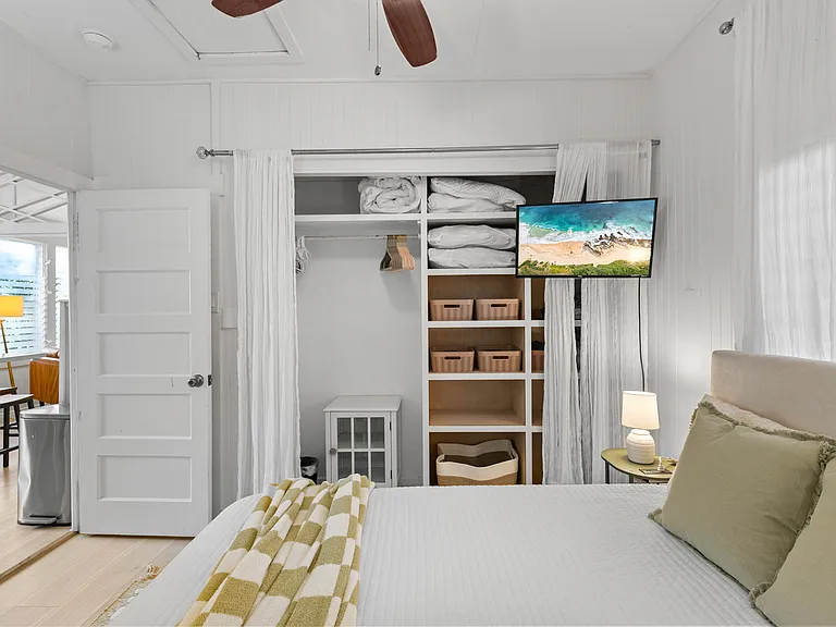 Back bedroom with double bed, AC, ceiling fan, dresser, side tables and large closet with built-in shelving.