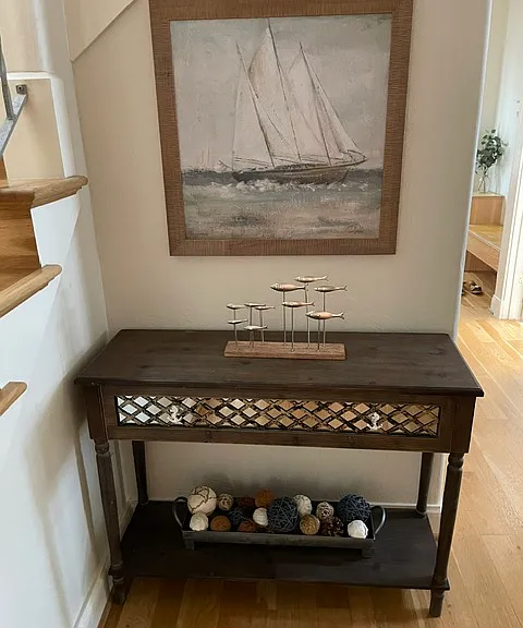 This is a side table in the hallway near the kitchen and next to the stairs leading up to the second floor bedrooms.