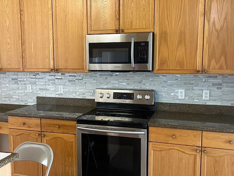 24 - Full kitchen view with wooden cabinetry and stainless steel appliances.
