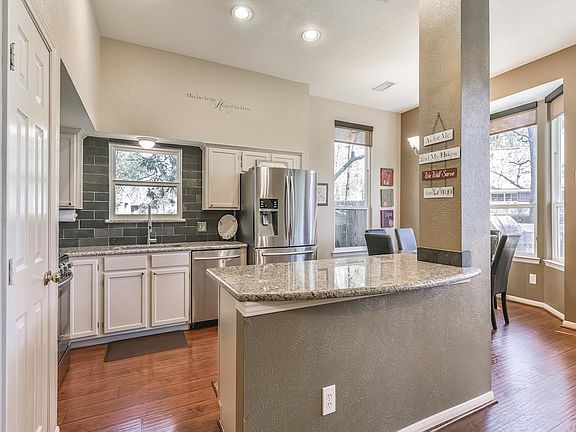 Island kitchen has breakfast bar and stainless appliances including a gas range.
