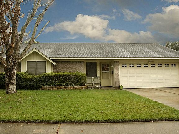 The front of this home is nicely manicured and has mature trees.