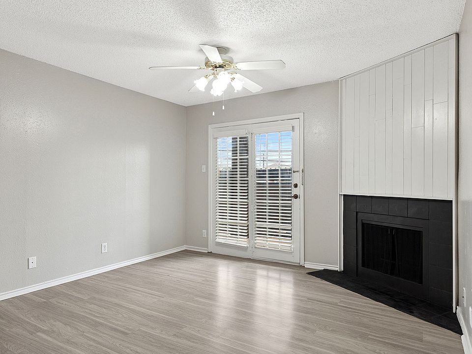 A bright living room is shown with vinyl floors, cozy fireplace, and view of private patio.