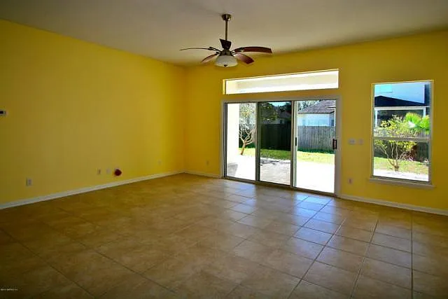 Great room facing back yard. Windows have blinds and patio has curtains