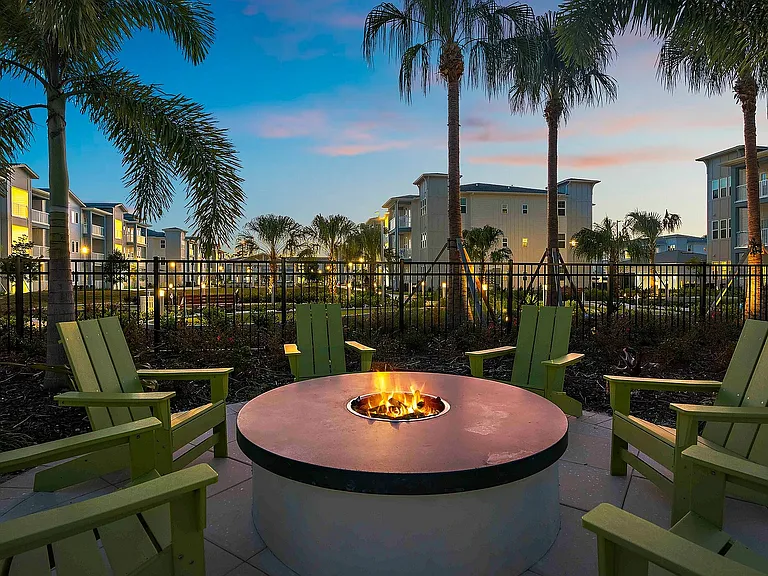 Relax in style with this luxurious outdoor fire pit setting, offering a perfect blend of comfort and tropical elegance.
