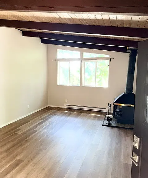 Light and bright living room with high wood beam ceilings and wood burning fire place. Brand new flooring.
